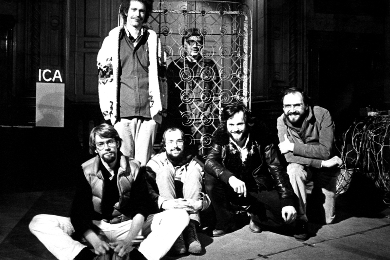 Composers Inside Electronics group photo at the ICA, with David Tudor visible through a metal lattice sculpture