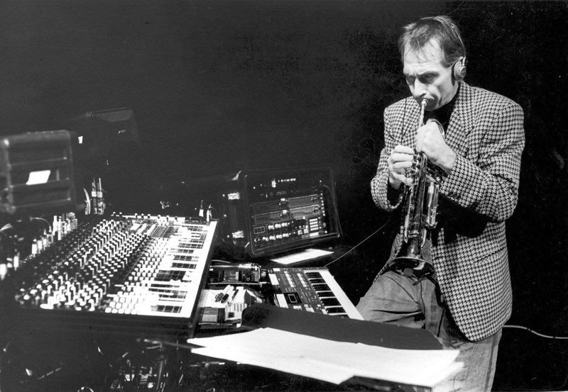 Jon Hassell playing trumpet through an effects rig, mixing console in the foreground