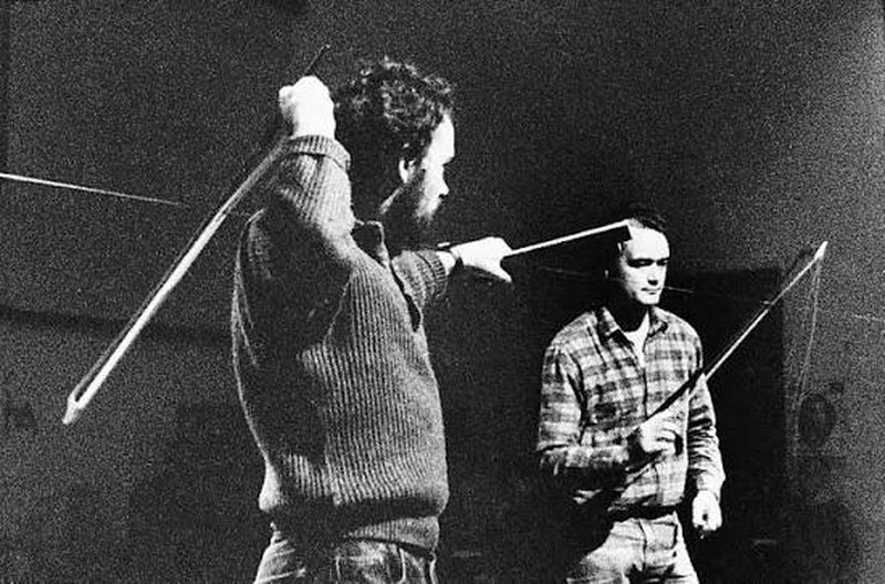 Still from Kick That Habit: two musicians bowing long wires as instruments