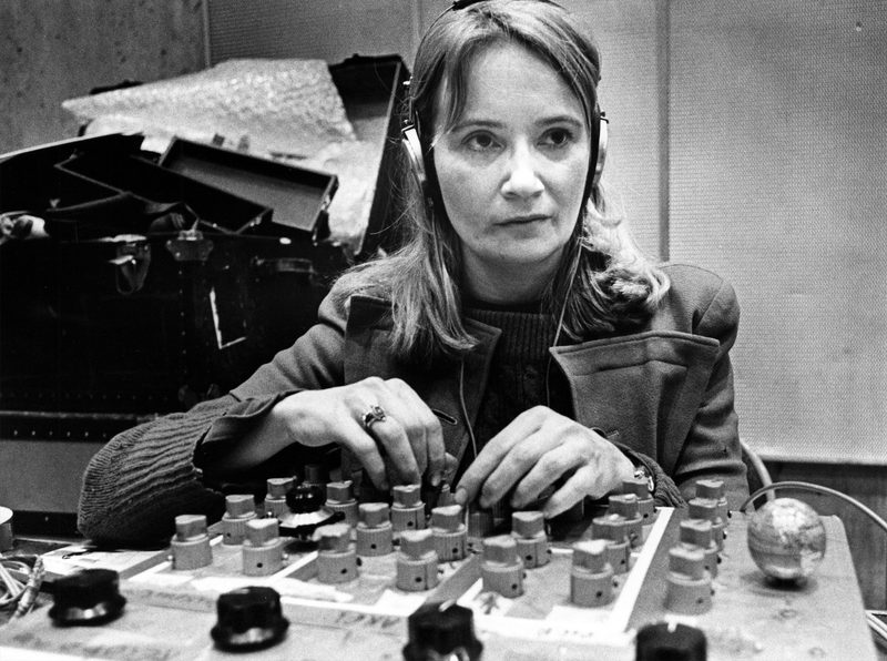 Maryanne Amacher wearing headphones, hands on a custom mixing console