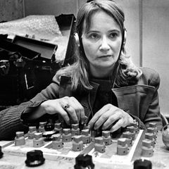 Maryanne Amacher wearing headphones, hands on a custom mixing console