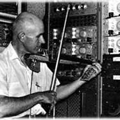 Max Mathews playing an electric violin he built, in his analog electronics lab at Bell Labs, circa 1970