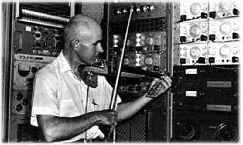 Max Mathews playing an electric violin he built, in his analog electronics lab at Bell Labs, circa 1970