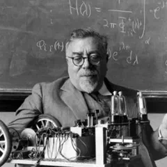 Norbert Wiener holding a cigar in front of a blackboard, with his Palomilla cybernetic moth on the table