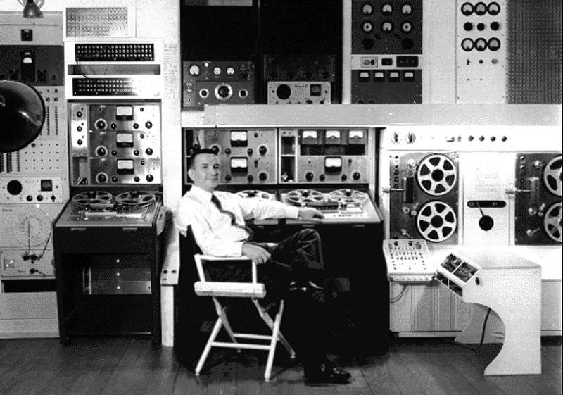 Raymond Scott seated among his reel-to-reel tape machines and electronic music equipment