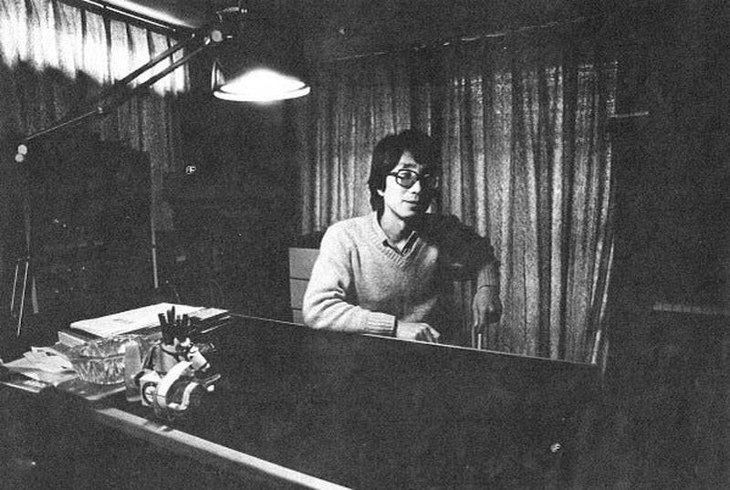Satoshi Ashikawa seated at a keyboard in a curtained studio